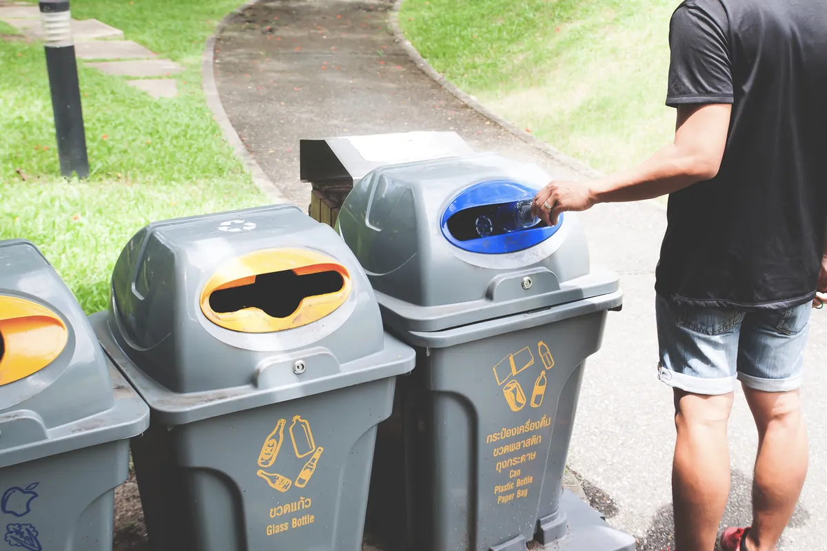 Person sorting waste into recycling bins for a waste disposal client