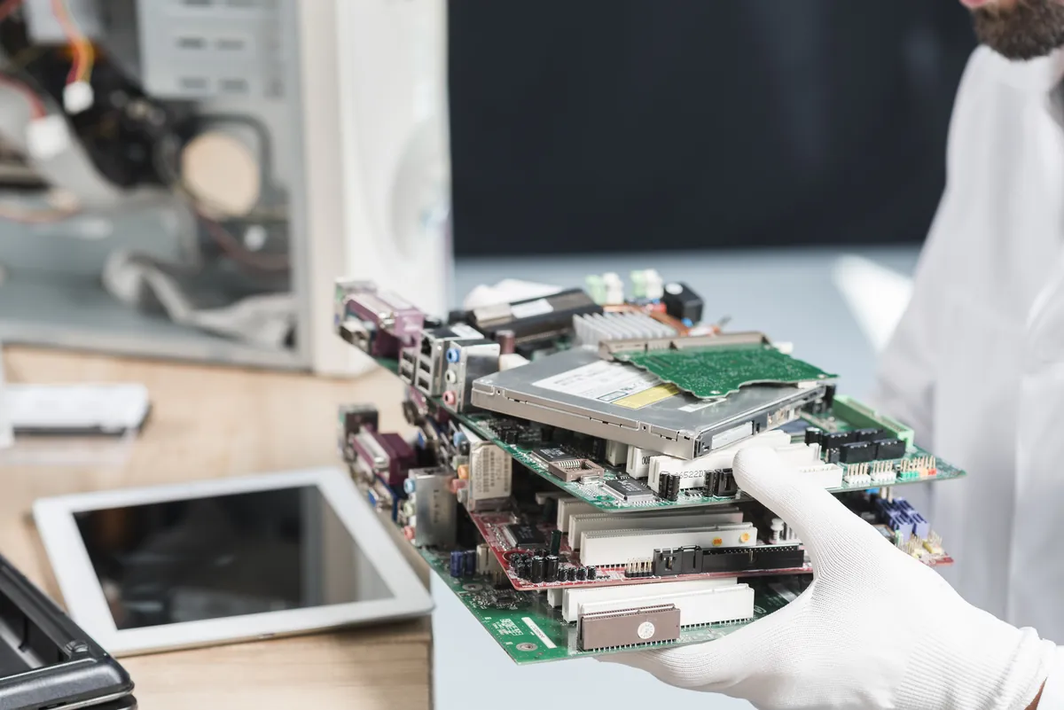 Technician holding old computer parts for e-waste disposal